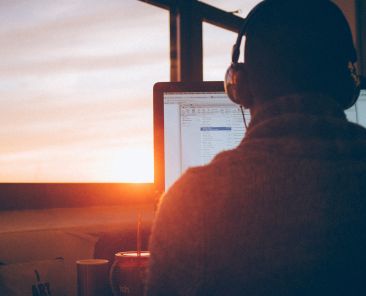a person wearing headphones and working on a computer at sunrise