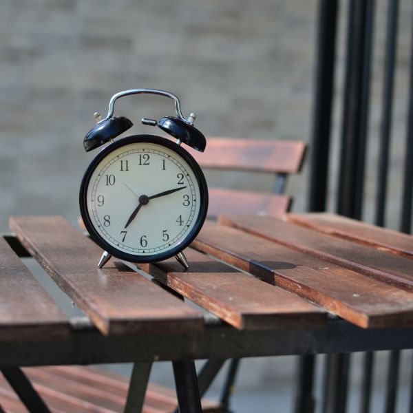 an alarm clock sitting on an outside wooden table