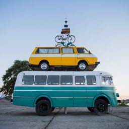bicycles on top of yellow mini van on top of a teal bus